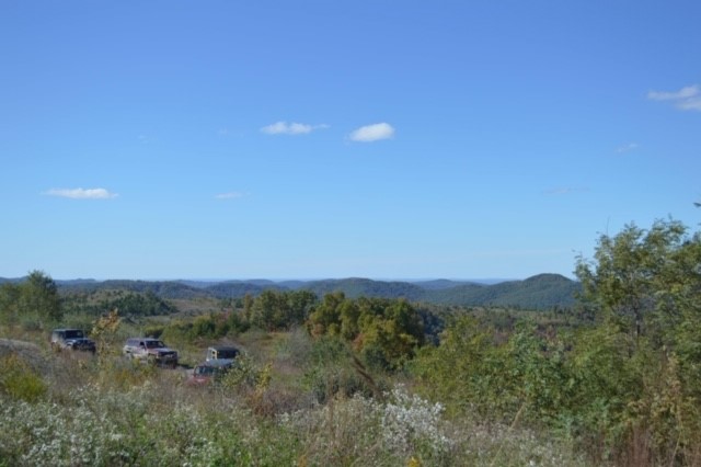 Vehicles gathered on a ridge with mountain panorama — Phase 1 work starting on the actual land